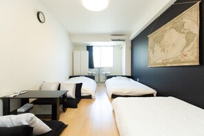 Habitación de hotel con dos camas, un escritorio, una silla, un mapa en la pared y una ventana con cortinas.