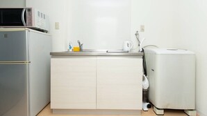 A compact kitchenette with a refrigerator, microwave, sink, and a small washing machine. - Guesthouse Daikokucho Ekimae (Osaka)