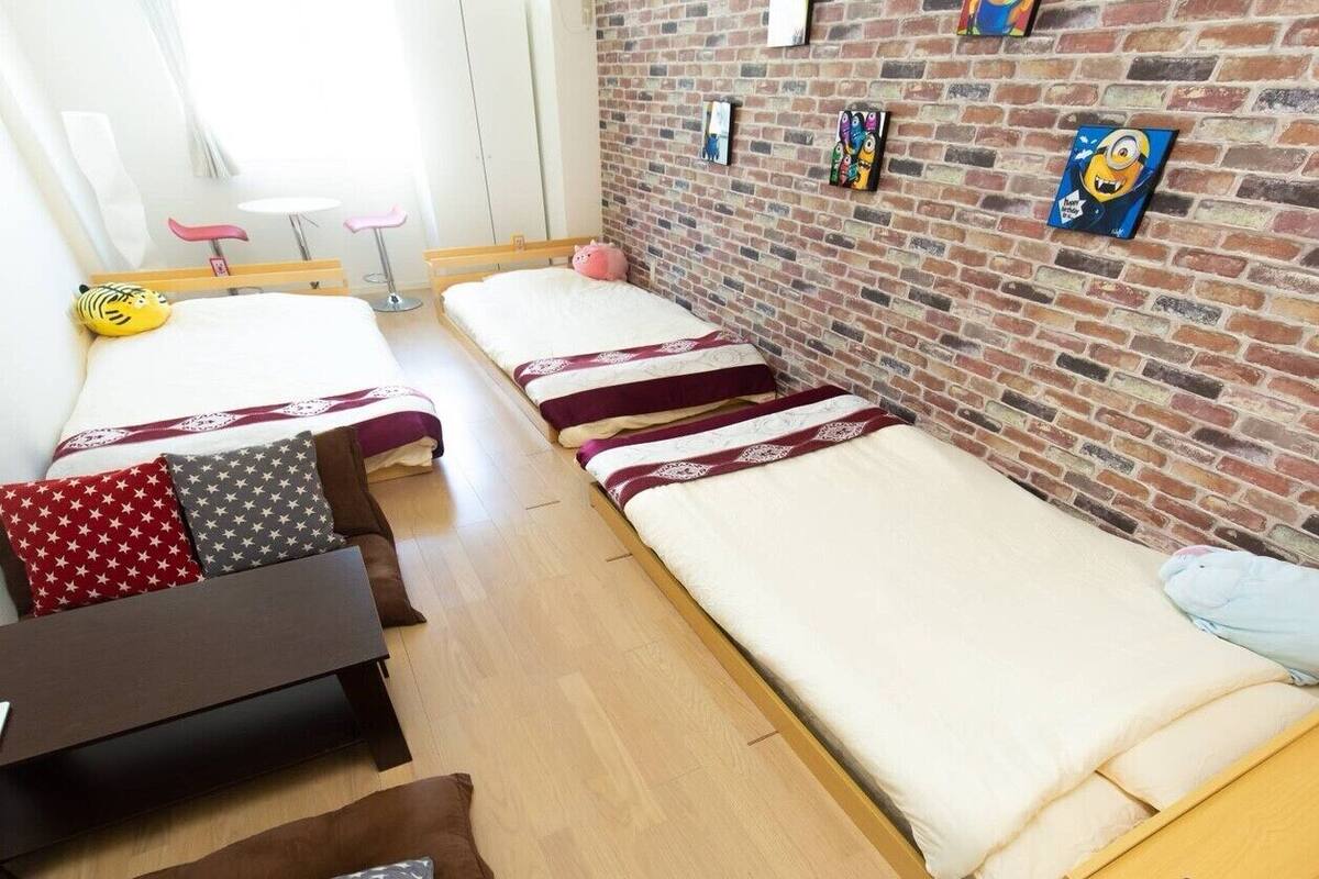 Una habitación con dos camas individuales, una mesita pequeña y un banco.