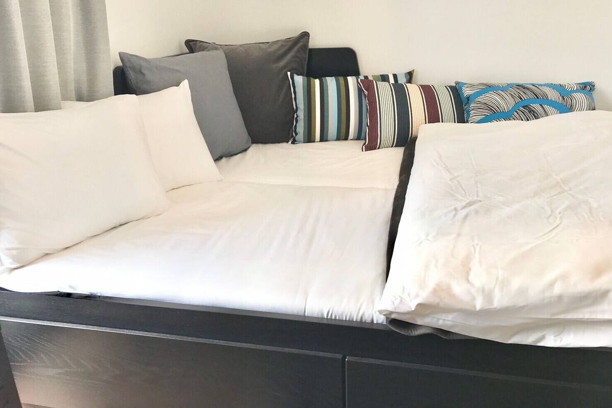 A bed with white bedding and multiple pillows in various colors and patterns.