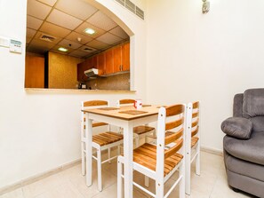 Ein Essbereich mit Holztisch und Stühlen, im Hintergrund eine Küche und ein graues Sofa.