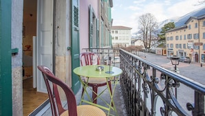 A balcony with a table and chairs, a view of the street and buildings, and a mountain in the background. - Midi Guestrooms (Martigny)