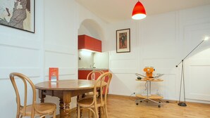 A dining area with a wooden table and chairs, a red pendant light, and a small table with a lamp. - Midi Guestrooms (Martigny)