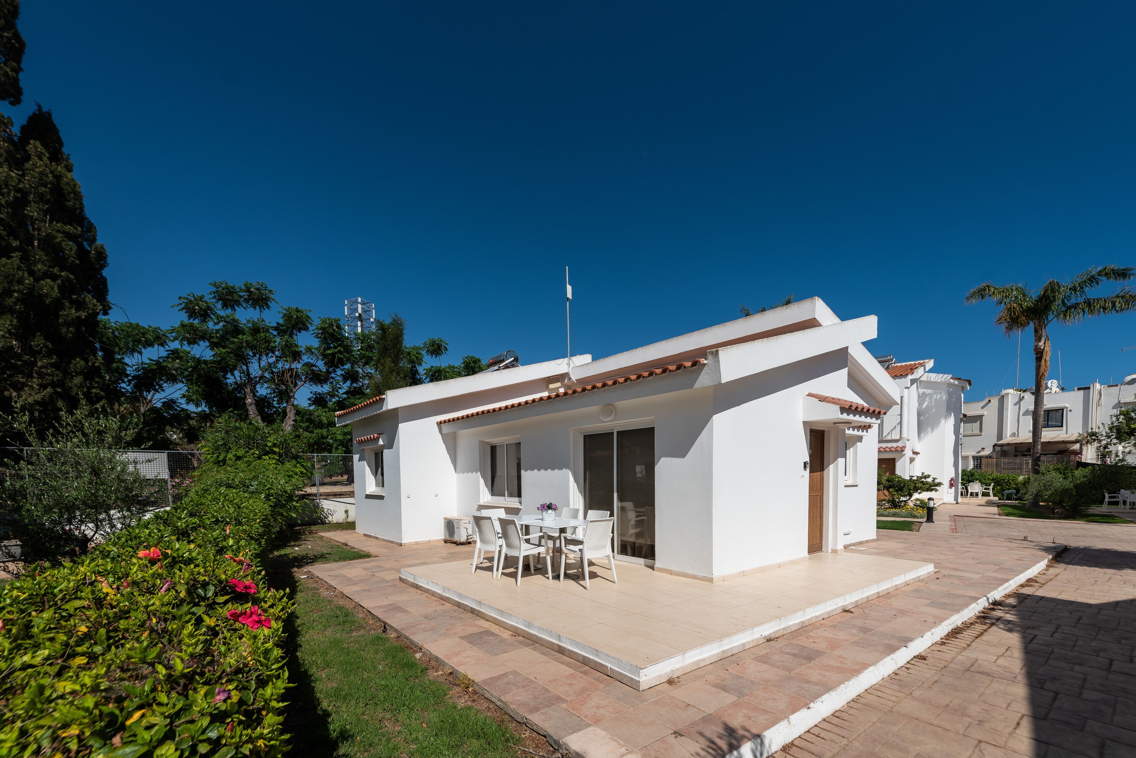 Eine moderne, weiße Villa mit Terrasse, Essbereich und einer Fahne auf dem Dach.