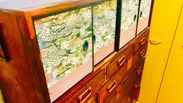 Une commode en bois avec une façade en verre sur laquelle est représentée une vue urbaine.