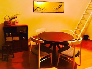 A dining area with a round table and four chairs, a small stool, a bookshelf, and a ladder against the wall. - Local Nakasu Apartment (Fukuoka)