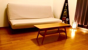 Une pièce avec un plancher en bois, un canapé beige et une table en bois.