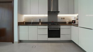 Una cocina moderna con gabinetes blancos, una campana extractora de acero inoxidable y un horno empotrado.