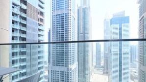 Un edificio alto con fachada de vidrio moderna, varios balcones y vistas a otros rascacielos.
