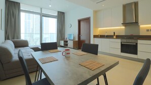 Una sala moderna con un sofá, una mesa de comedor con individuales, una taza de café y una cocina con armarios y una estufa.