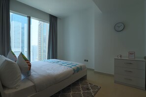 Een moderne hotelkamer met een groot bed, een nachtkastje, een klok aan de muur en een raam met gordijnen.