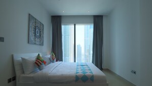 Habitación de hotel moderna con una cama grande, vistas a la ciudad y una alfombra con estampado geométrico.