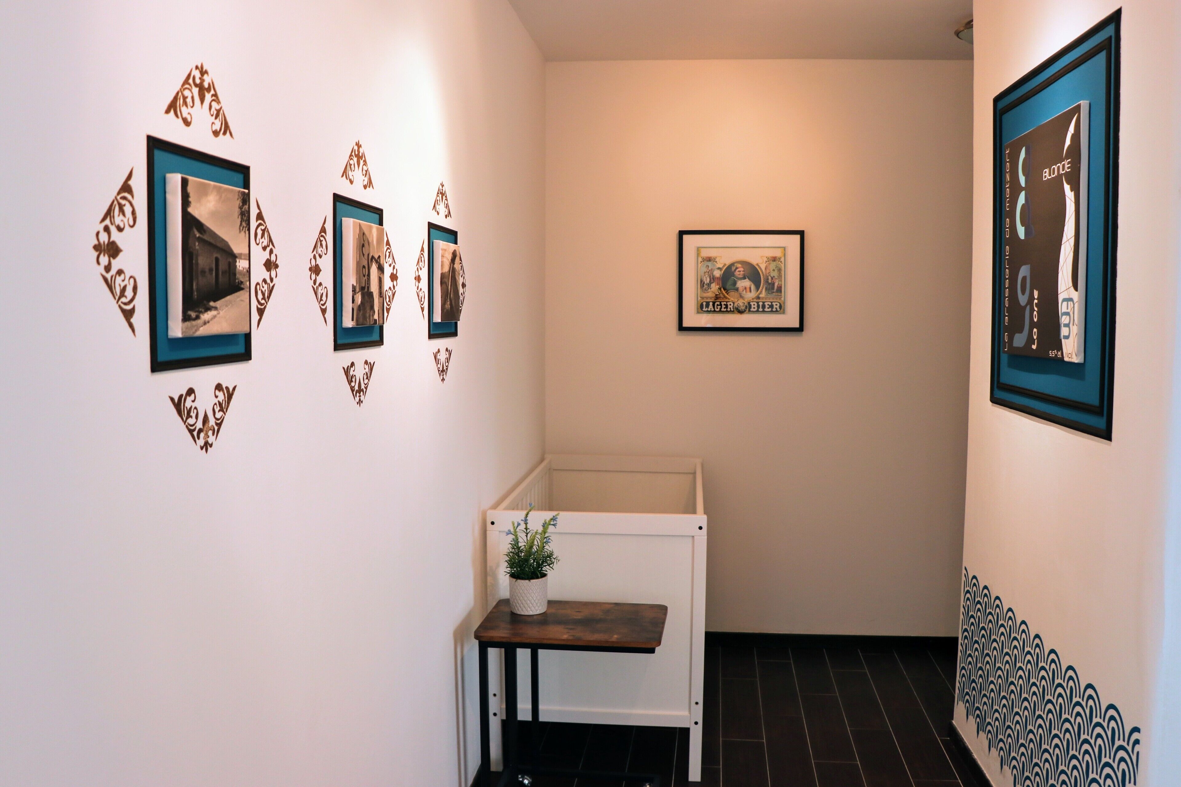 A hallway with framed pictures on the walls, a small table with a plant, and a white bench.