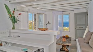 Quarto moderno com toucador branco, parede de pedra e vista para o mar.