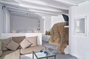 Un salón moderno con un sofá color beige, una mesa de centro de vidrio y una gran formación rocosa.