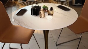 A modern living room with a round white table, two brown leather chairs, a black sofa, and a decorative glass vase with flowers. - Hôtel du MontLouis (Paris)