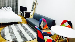 Ein modernes Hotelzimmer mit Bett, Sofa, Fernseher und einem kleinen Tisch.
