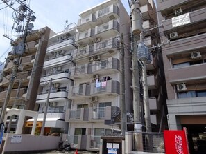 A multi-story residential building with balconies, air conditioning units, and visible signage. - Local Gion Apartment (Fukuoka)
