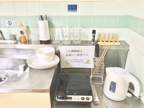 Eine Küchenarbeitsplatte mit einem Reiskocher, einem Wasserkocher und einem Schild, das daraufhinweist, dass der Kocher ausschließlich zum Wasser kochen dient.