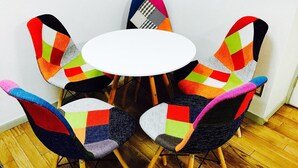 Ein runder Tisch, umgeben von fünf Stühlen mit bunten geometrischen Mustern.