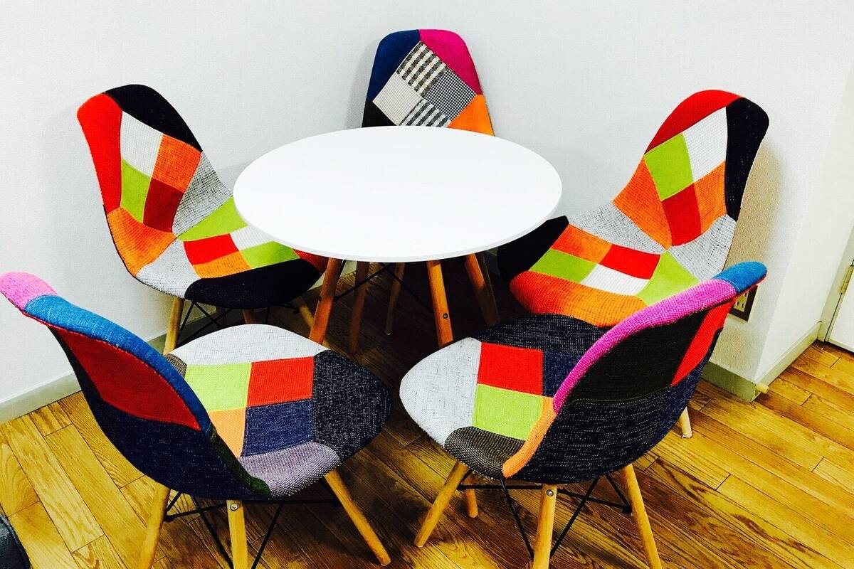 A round table surrounded by five chairs with colorful geometric patterns.
