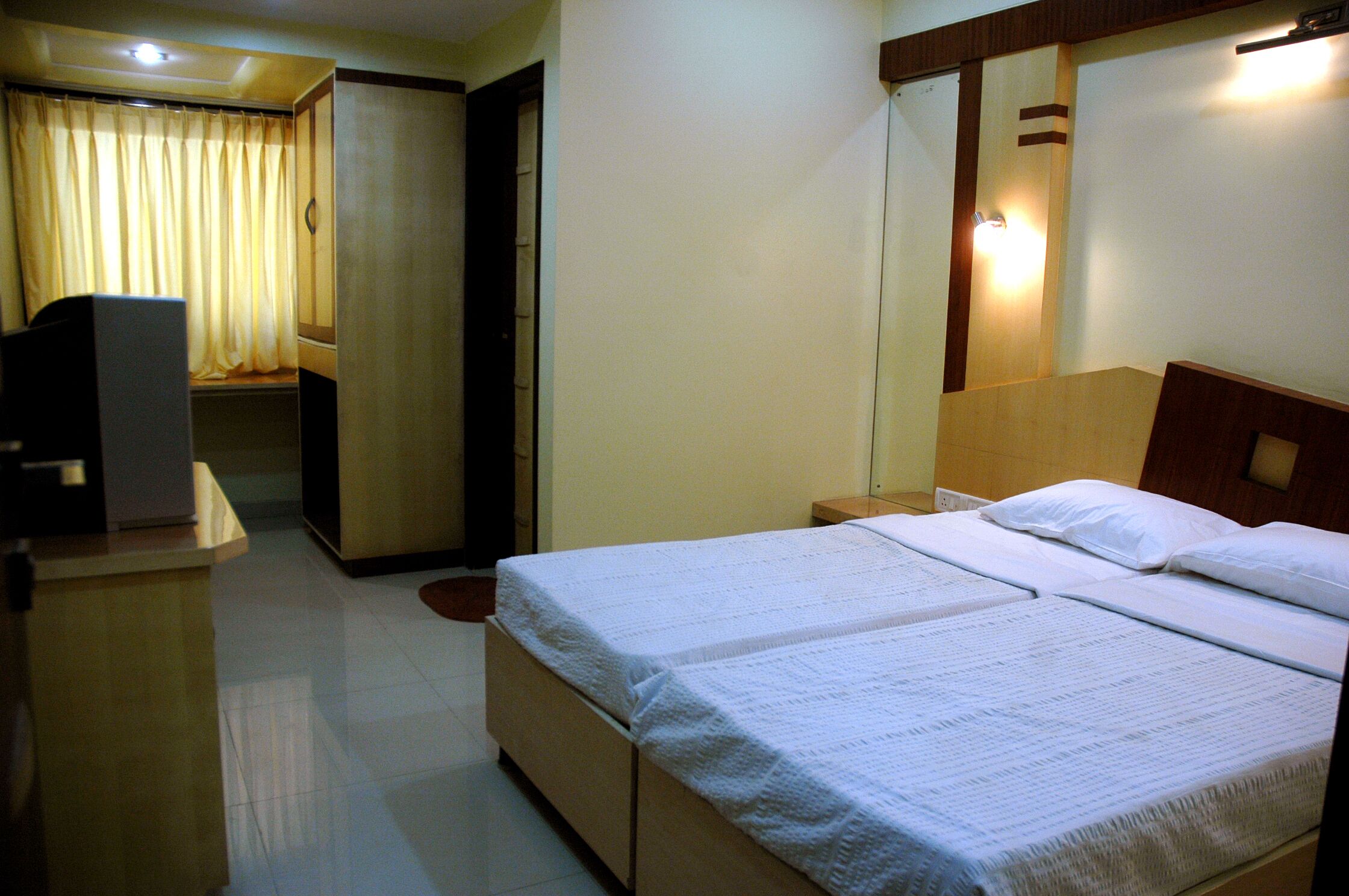 A hotel room with a bed, a desk, a wardrobe, and a mirror.