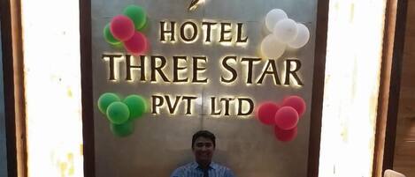 A reception desk with a sign for "Hotel Three Star Pvt Ltd" and a logo above it.