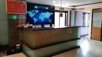 Bancada de recepção com um mapa-múndi, um relógio e um painel exibindo taxas de câmbio.