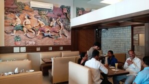 A restaurant with a mural of traditional scenes, booths, and a high ceiling. - Hotel Three Star Pvt Ltd (Panvel)