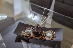 A modern table with a dark vase, two small candle holders labeled "Wish" and "Love," and a tray of smooth stones.