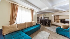 A modern living room with a sectional sofa, a TV, and a dining area with chairs and a table.