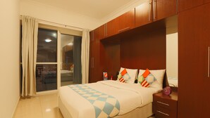 A bedroom with a bed, a nightstand, a wardrobe, and a sliding glass door to the outside. - OYO Home 260 Studio Saba 3 Tower (Dubai)