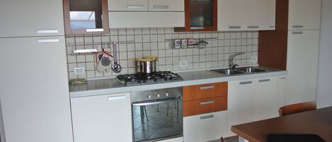 Réfrigérateur, un four, surface de cuisson, vaisselle et ustensiles