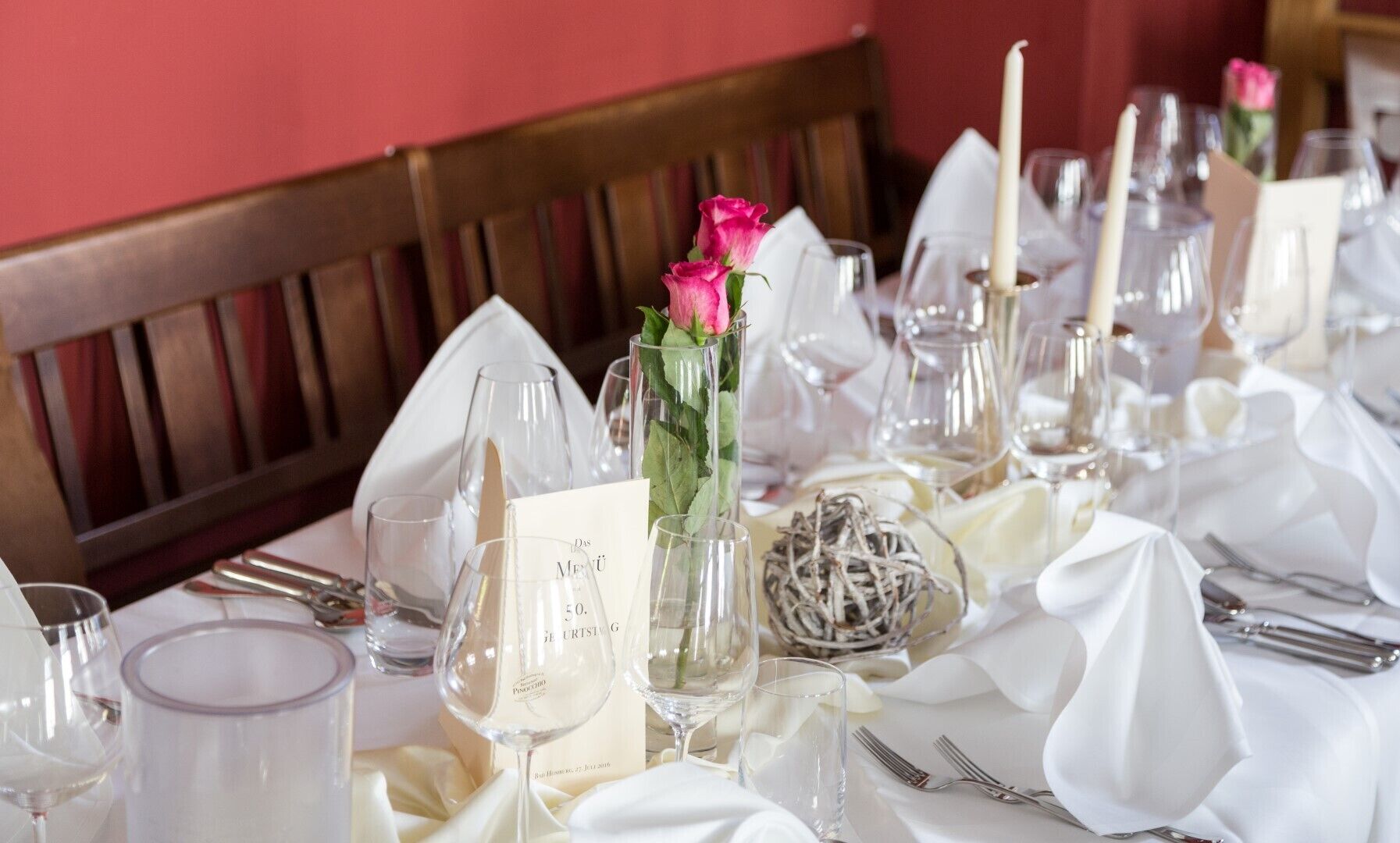 Una mesa dispuesta para una cena formal, con copas de cristal, servilletas blancas y una tarjeta de menú.