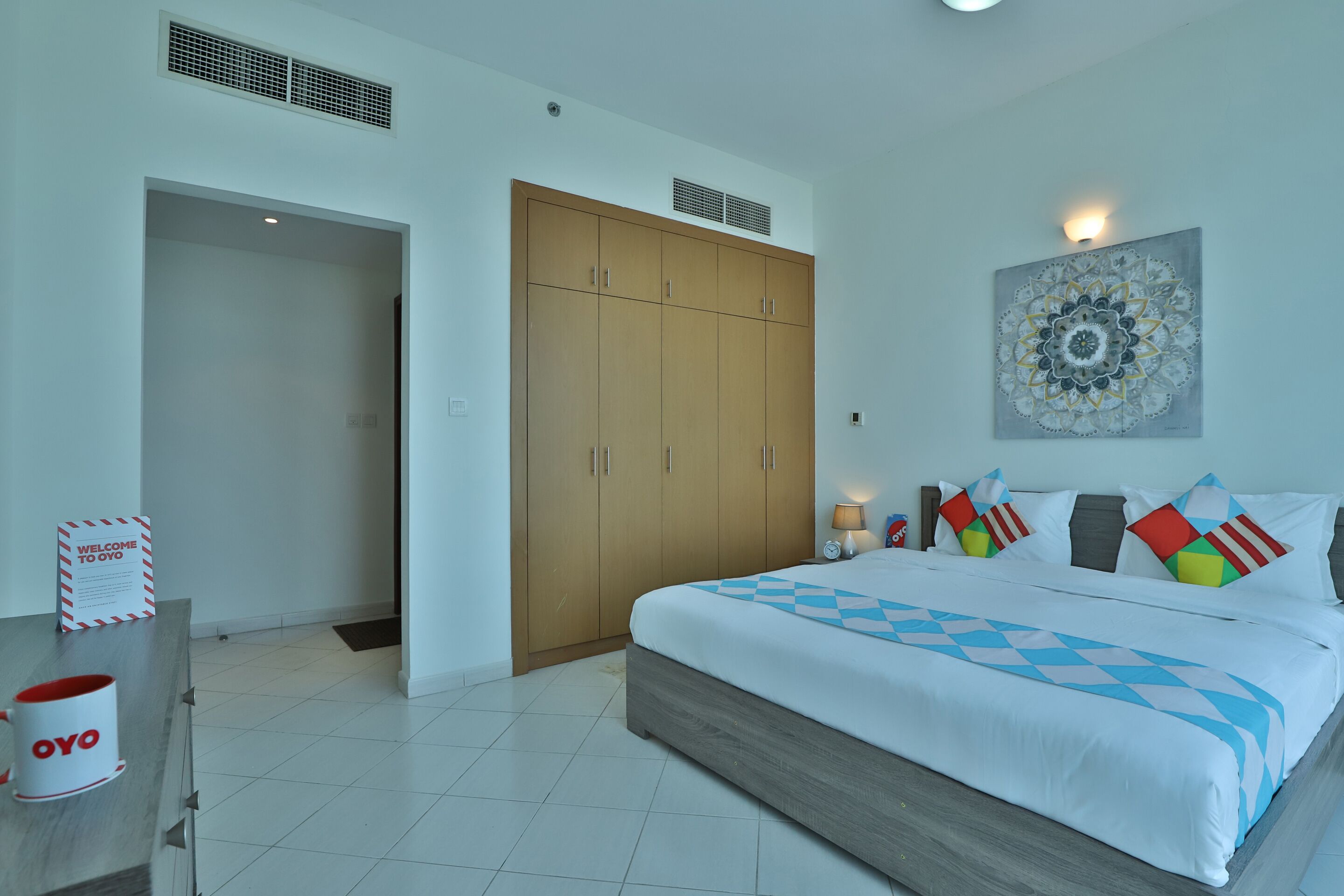 A hotel room with a bed, wardrobe, and a welcome sign.