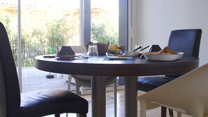 A dining table with a laptop, a bowl of fruit, and a plate of food. - Chambres D'hôtes 1001 Nuits (Vendays-Montalivet)