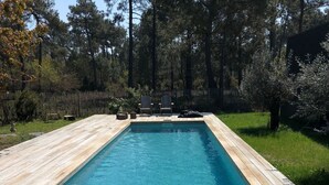 A rectangular swimming pool with a wooden deck surrounding it. - Chambres D'hôtes 1001 Nuits (Vendays-Montalivet)