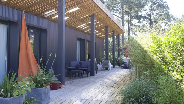 A covered outdoor area with seating and planters, surrounded by trees. - Chambres D'hôtes 1001 Nuits (Vendays-Montalivet)