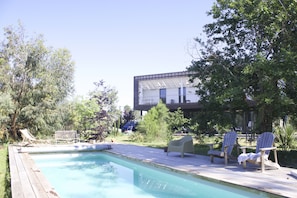Un espace piscine avec des chaises longues et une terrasse.