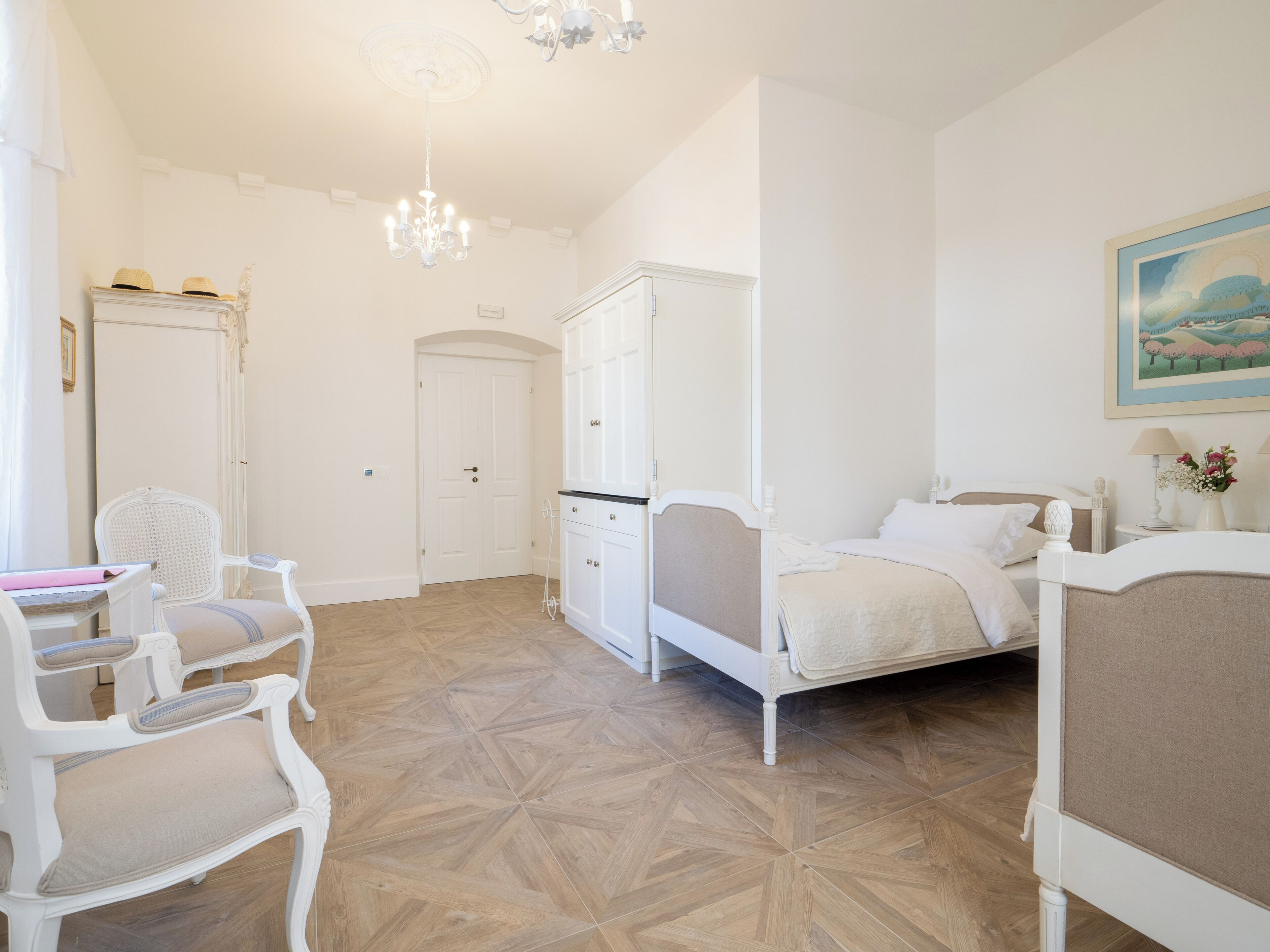 Un dormitorio con una cama, una silla, un armario y una araña.