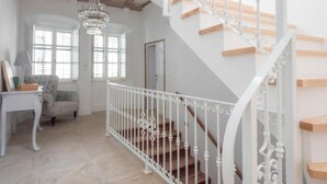 Een ruime woonkamer met een trap voorzien van witte leuningen en houten treden.