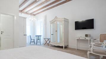 Une chambre avec un grand lit, une armoire, une télévision et un coin repas avec des chaises.