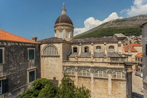 Un bâtiment historique doté d’un dôme et de fenêtres en arc de cercle, entouré d’autres bâtiments et situé au pied d’une colline.