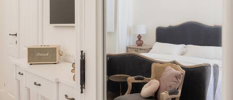 Un dormitorio con cama, una silla, cómoda y espejo.