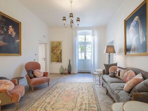 Un salon avec un lustre, un canapé, un fauteuil et un tapis.
