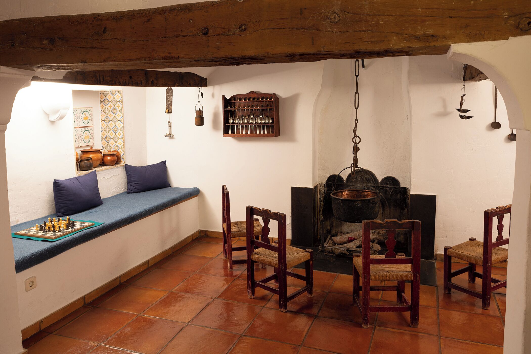 A cozy room with a built-in bench, a fireplace, and a chessboard.