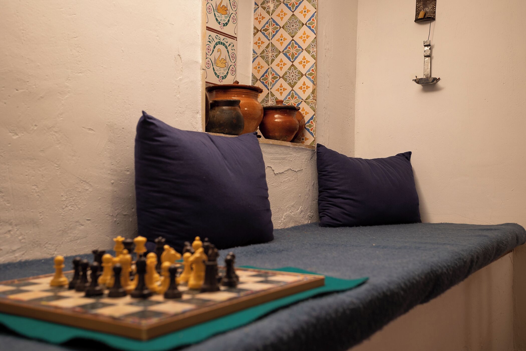 A room with a bed, pillows, a chessboard, and decorative tiles.
