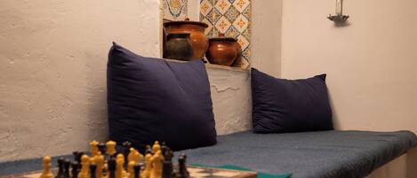 A room with a bed, pillows, a chessboard, and decorative tiles.