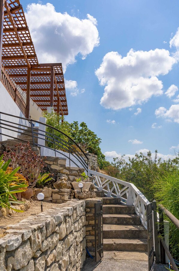A stone staircase leading up to a wooden pergola with a metal railing.