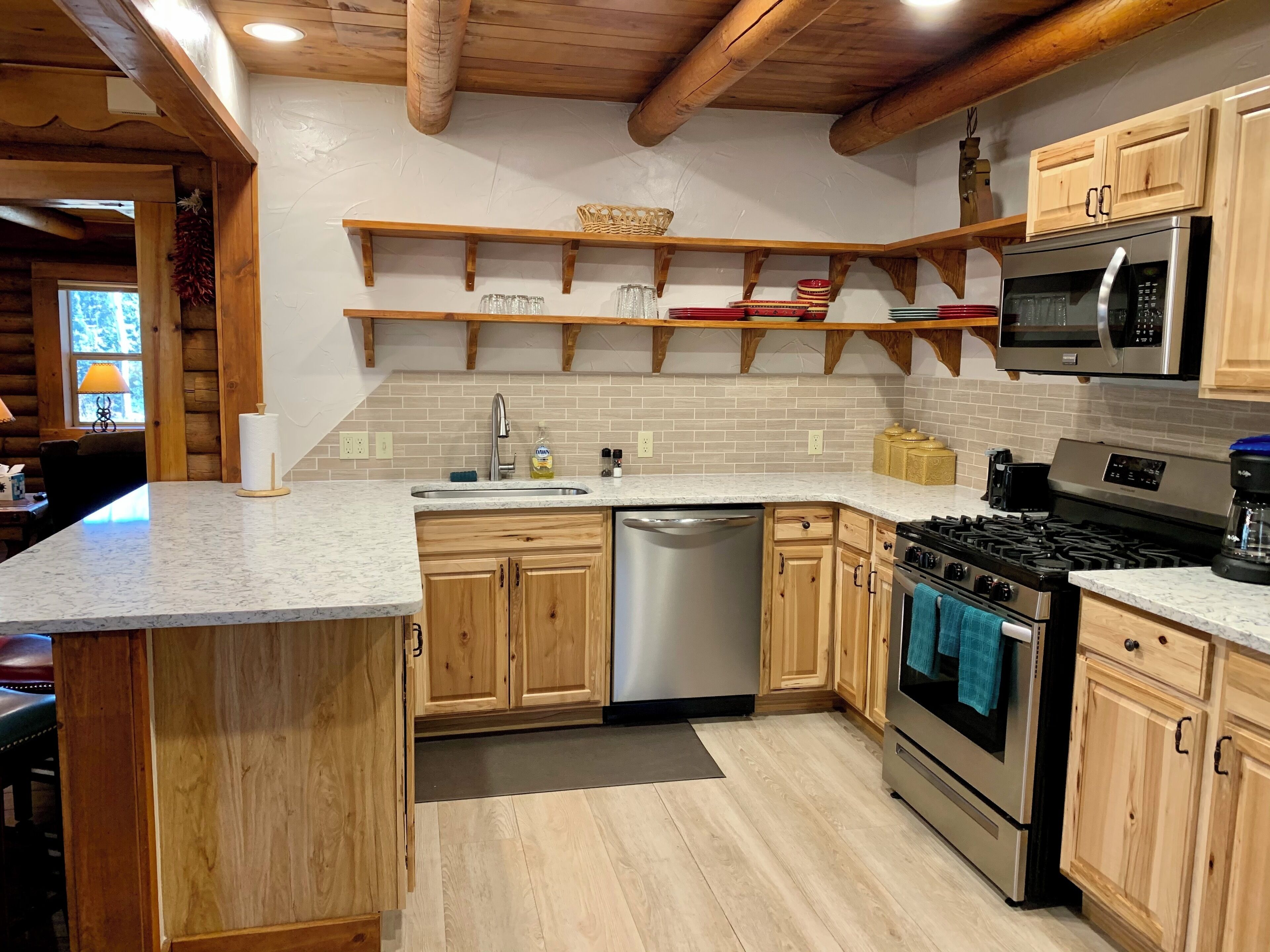A modern kitchen with wooden cabinets, a stainless steel dishwasher, a gas stove, and a microwave.